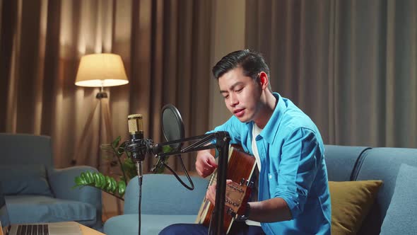 Asian Man Playing Guitar While Streaming For His Social Media Channel alt