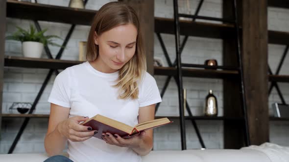 Beautiful Young Woman Reading a Book on the Sofa alt