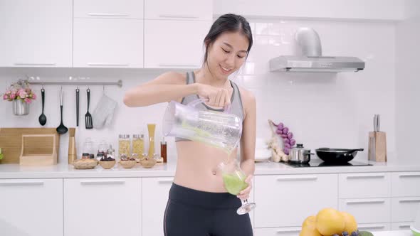 Asian woman drinking apple juice in the kitchen use organic fruits alt