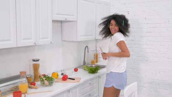 Positive woman cooking at the kitchen, dancing and having fun.