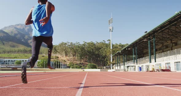 Disabled mixed race man with prosthetic legs running on race track alt