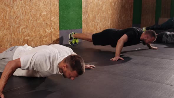 Strong Fit Athletic Men Doing Push Up Exercises in a Loft Style Industrial Gym alt