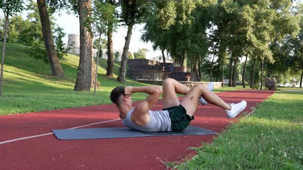 Athlete Guy Doing Bicycle Exercise for Abs Muscles Outdoor Training alt