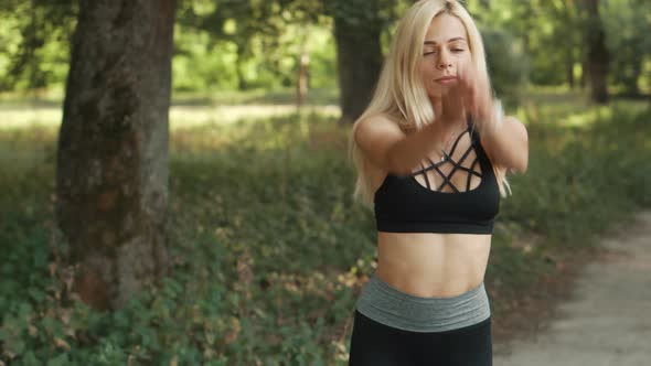 Young Woman Warming Up Before Jogging in Park alt