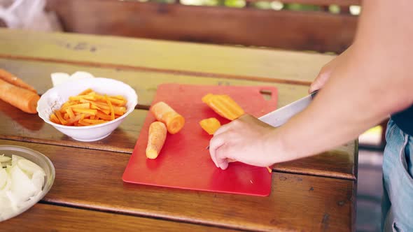 Closeup The Guy is Cooking Pilaf Is in the Summer House Cuts Carrots alt