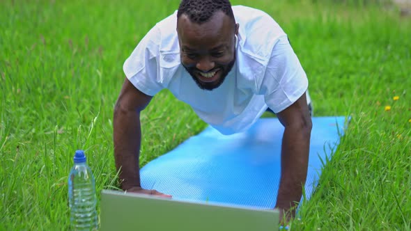 Happy Young Adult Man in the Park Having Online Training