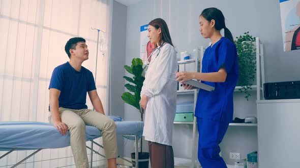 Asian specialist doctor and assistant nurse take care of male patient. alt