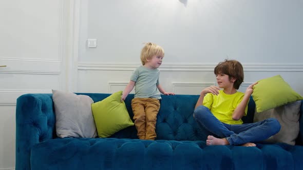 Little Blond Boy and His Brother Fight with Pillows at Home alt