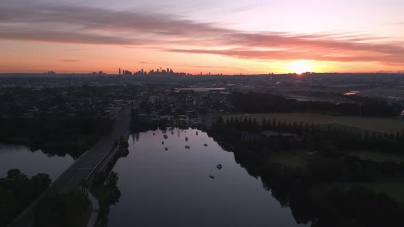 Aerial view of the skyline in the suburb of Sydney with cityscape in the silhouette, during sunrise. alt