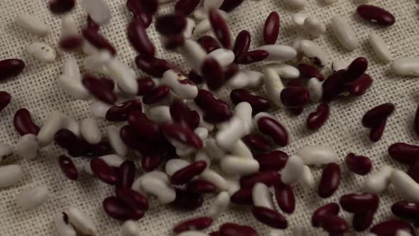  White and red beans on white burlap, slow motion