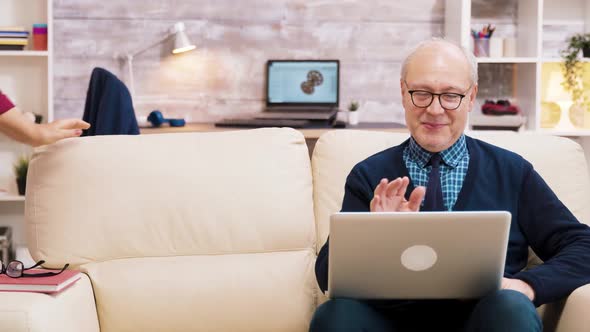 Happy Senior Middle Aged Couple Sitting on Sofa Having a Video Call alt