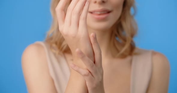 Blonde Pretty Woman Applies Skincare Cream to Her Hands alt
