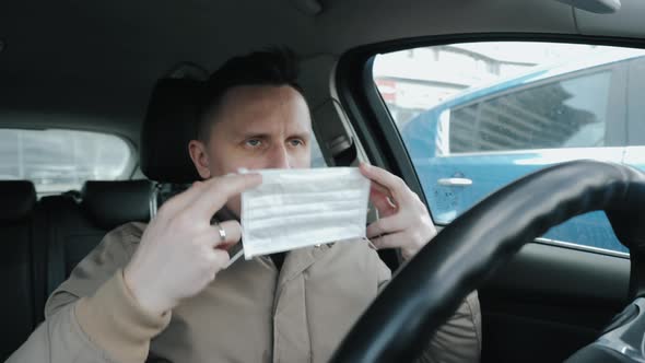 A Man Puts on a Medical Mask in His Car