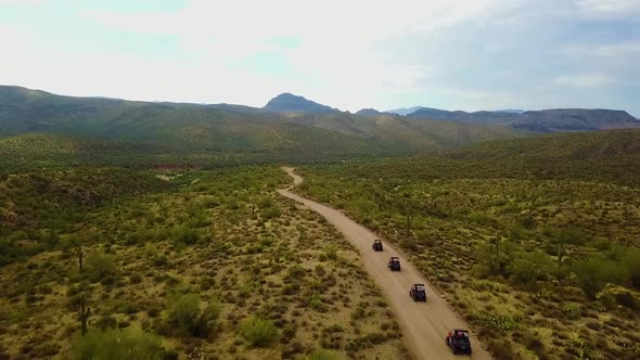 Aerial drone shot of four UTV's driving through the Arizona desert on a cloudy day alt