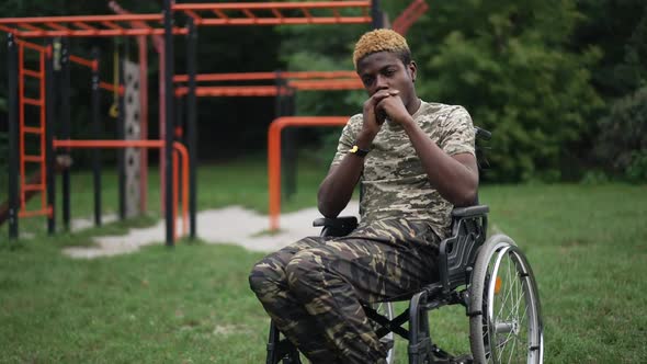 Devastated Frustrated Man in Wheelchair Sitting Outdoors in Park at Sports Ground Thinking alt