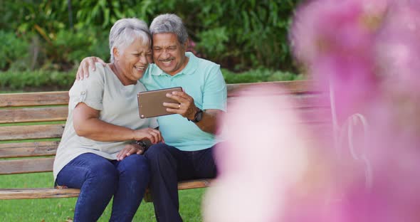 Video of happy biracial senior couple using tablet in garden alt