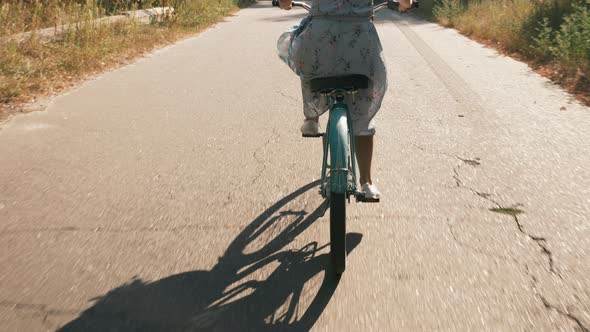 Woman cyclist is cycling on vintage old bike at sunset. Female cycling alt