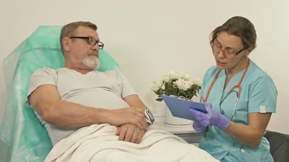 A Female Doctor Talks To an Elderly Patient in a Hospital Ward alt