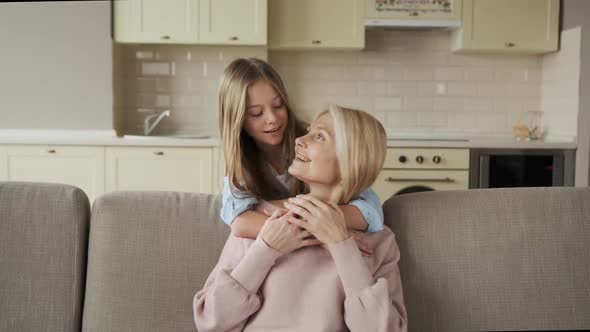 Little Girl Hugging Her Grandmother Sitting on the Couch alt