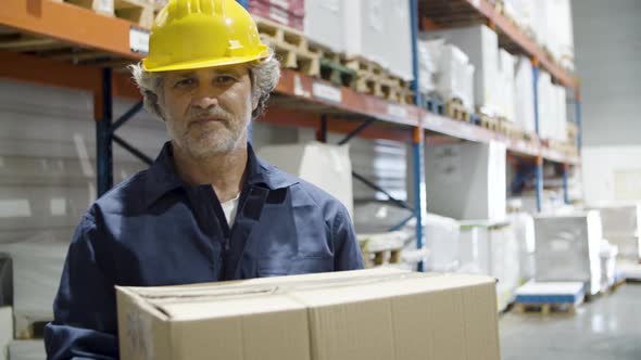 Focused Male Employee Holding Cardboard Box in Storehouse alt