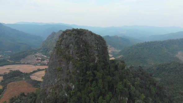 Aerial: flying over rice paddies unique valley scenic cliffs rock pinnacles tropical jungle Laos alt
