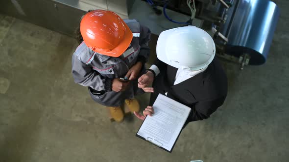 Two people in production are talking about work. Top view of helmets alt