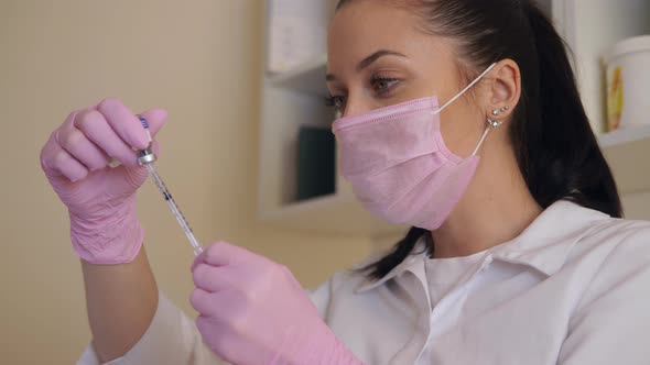 Female Beautician in Gloves and a Mask on the Face Prepares the Syringe for the Procedure