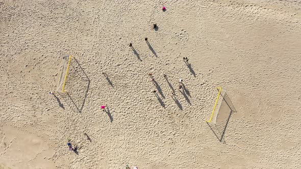 AERIAL: Rotating Shot of People Standing in Football Court with Long Shadows on Sand