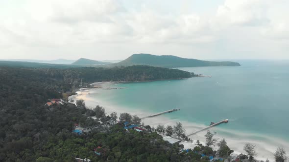 Wooden beach piers entering the blue shallow sea in the paradisiac Saracen Bay in Koh Rong Sanloem alt