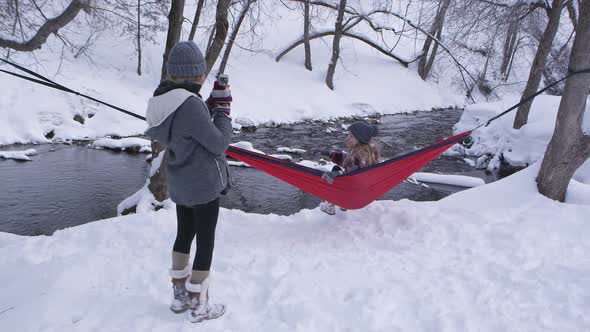 Girl swinging in hammock posing for picture in the snow alt