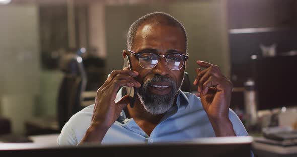 Professional businessman removing his glasses while talking on his phone in modern office in slow mo alt