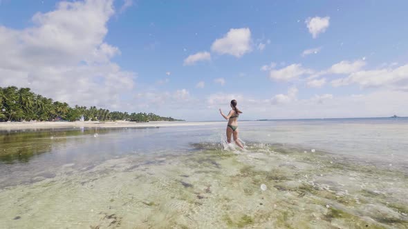 Joyful Young Woman in Swimsuit Running on Sea Water on Summer Beach alt
