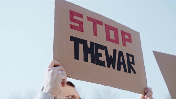 Man Holds a Poster with the Quote Stop the War alt