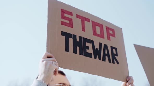 Man Holds a Poster with the Quote Stop the War