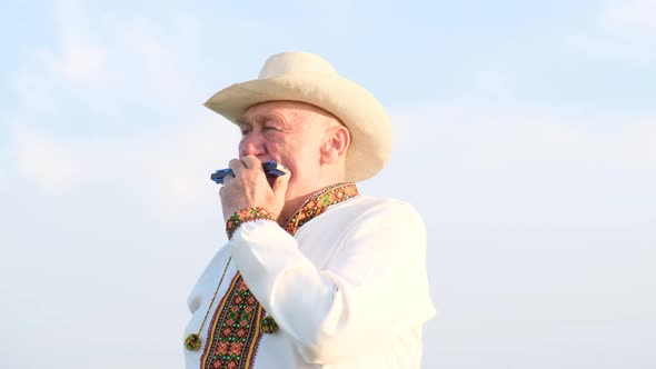 Portrait of an Elderly Ukrainian Man in an Embroidered Jacket Playing the Harmonica alt