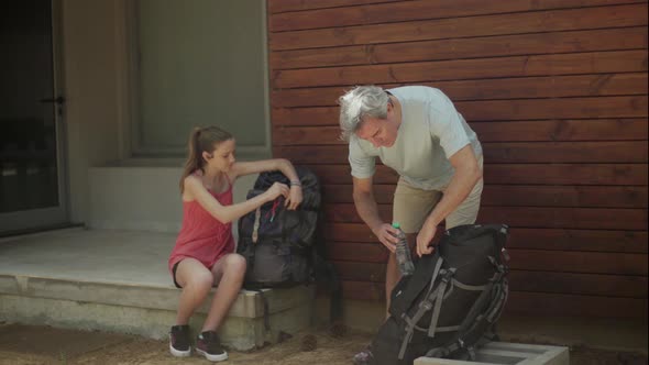 Father and daughter packing backpacks and embarking on trip