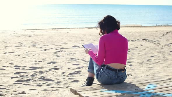 Dressed Girl Reading a Book on the Beach