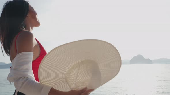 Woman Putting On Sun Hat While Walking In Sea Off Entalula Beach alt