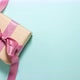 Gift box with a purple ribbon bow on blue background on the left side. Flat lay top view stop motion - VideoHive Item for Sale