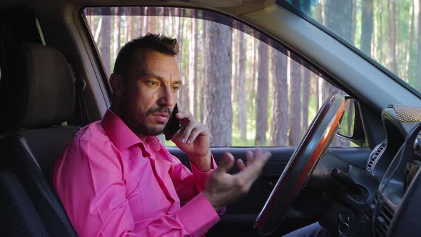 Serious Businessman Talking on the Phone While Driving a Car and Getting Angry alt