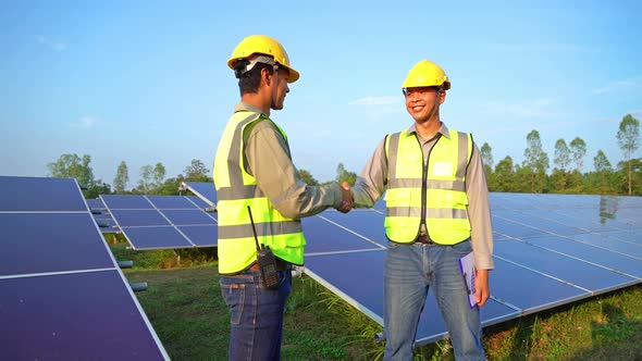 Engineer man or workers shake hands, people, with solar panels or solar cells on the roof in farm. alt