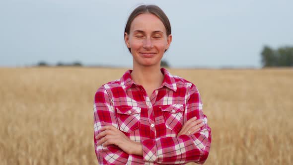 Portrait of a Pretty Farmer Woman with Her Arms Crossed Standing in a Wheat Field and Looking at the alt