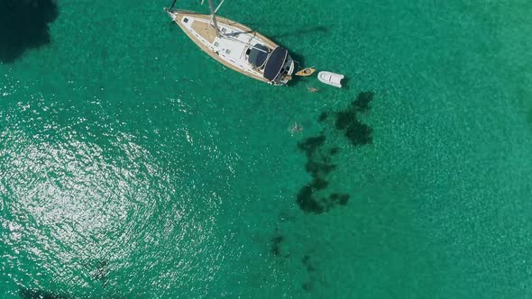 Aerial view above of single sailboat anchored in the mediterranean sea, Greece. alt