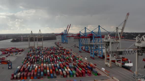 Slow Aerial Dolly in View of Large Cargo Cranes Above Rows of Colorful Containers in Hamburg alt