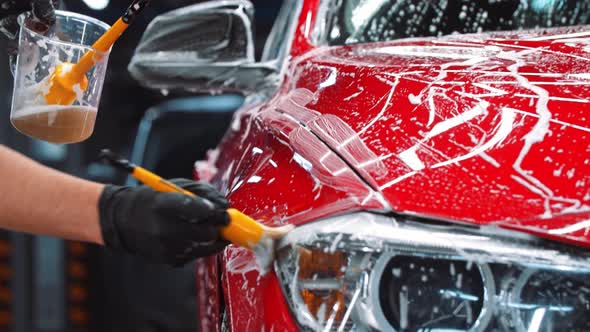 Auto Cleaning Service  Man Applying a Cleaning Solution on the Red Car alt
