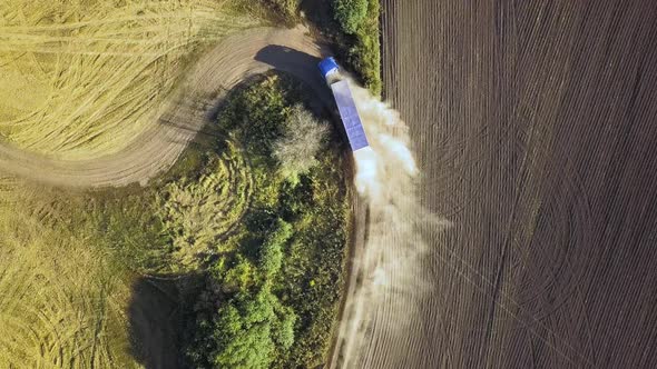 Top Down Aerial View of Fast Driving Car on Dirt Road Leaving Cloud of Dust Behind alt