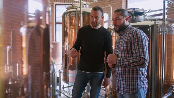 Two Male Brewery Workers Talking Admiring New Shiny Equipment alt