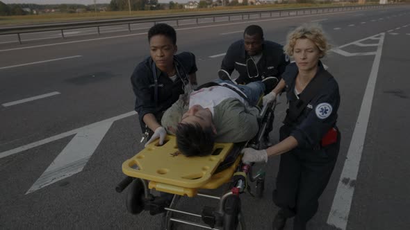 Multiracial Paramedic Transporting Injured Man on Stretcher alt