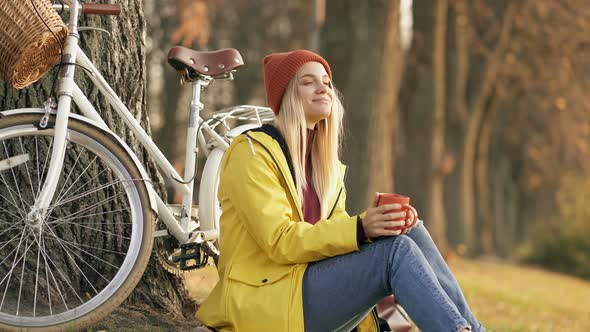 Woman Sitting on The Ground Near the Tree and Bicycle