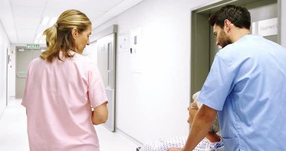 Nurse pushing a patient in a wheelchair while talking to a doctor alt